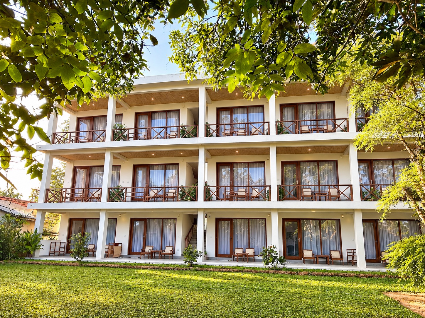 Lily Mirissa's finished three-storey building seen from the garden, framed by tall tropical trees