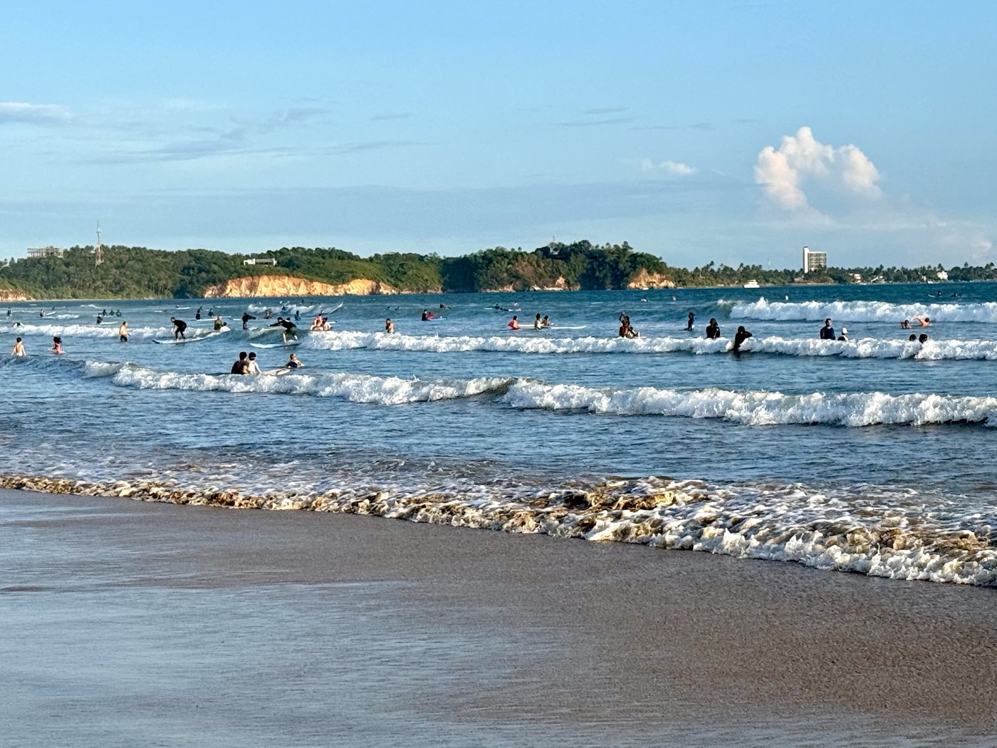 Surfers riding gentle waves at Weligama Bay